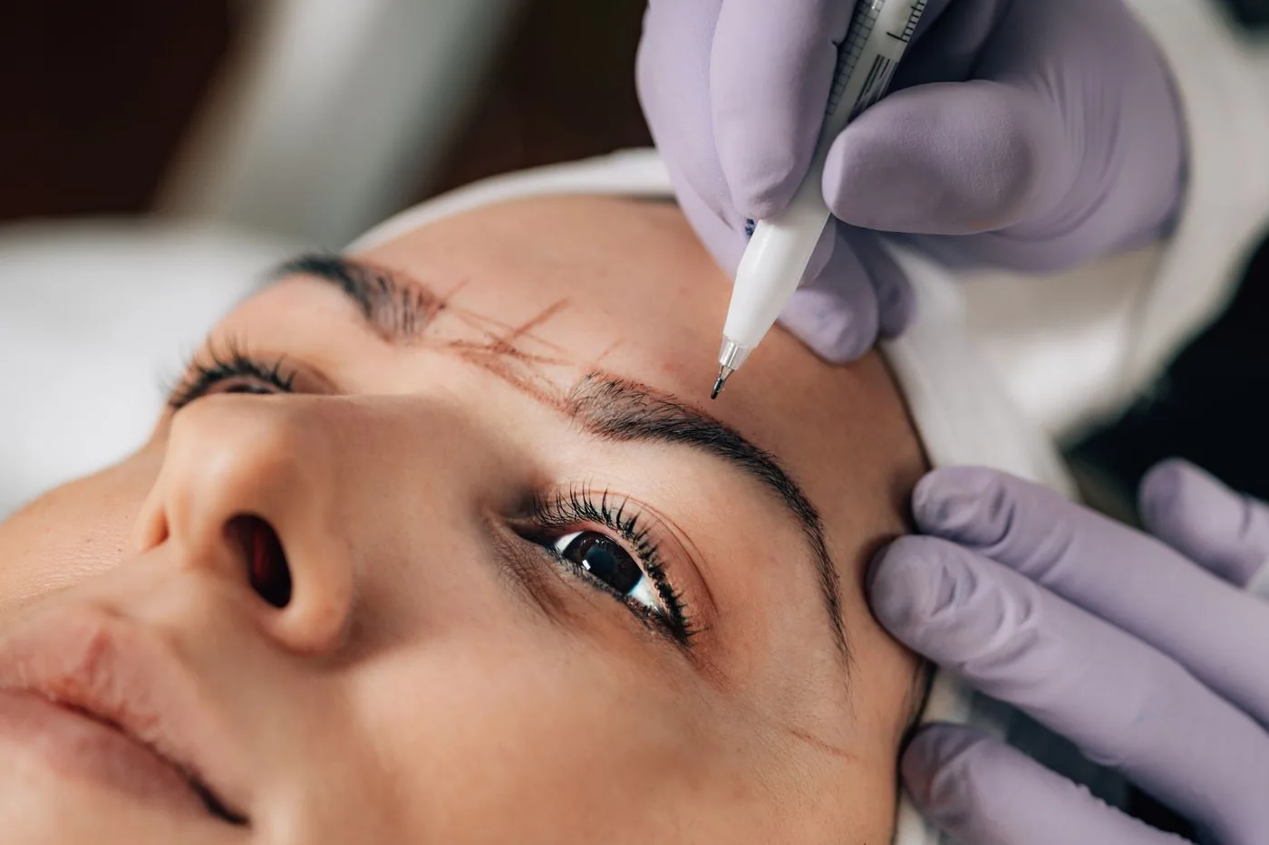 Gloved practitioner working precisely along a client’s brow